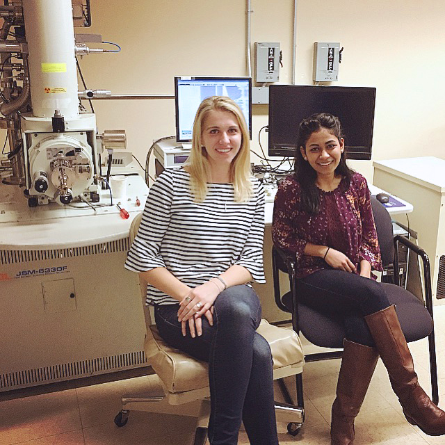 (From left to right) Amanda Giroux and Hetal Patel in front of Scanning Electron Microscope at Professor Lee’s laboratory.