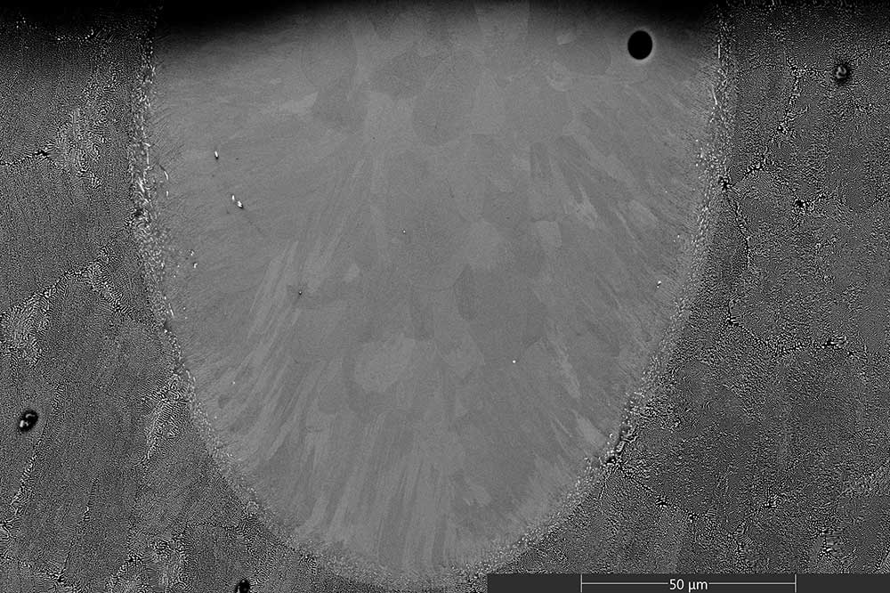 A back-scattered SEM image of a cross-sectioned melt track made by laser glazing an Al-3Ce at% substrate. It shows the unmelted state towards the left, right, and bottom edges and the effect that rapid local melting and solidification has on the microstructure.