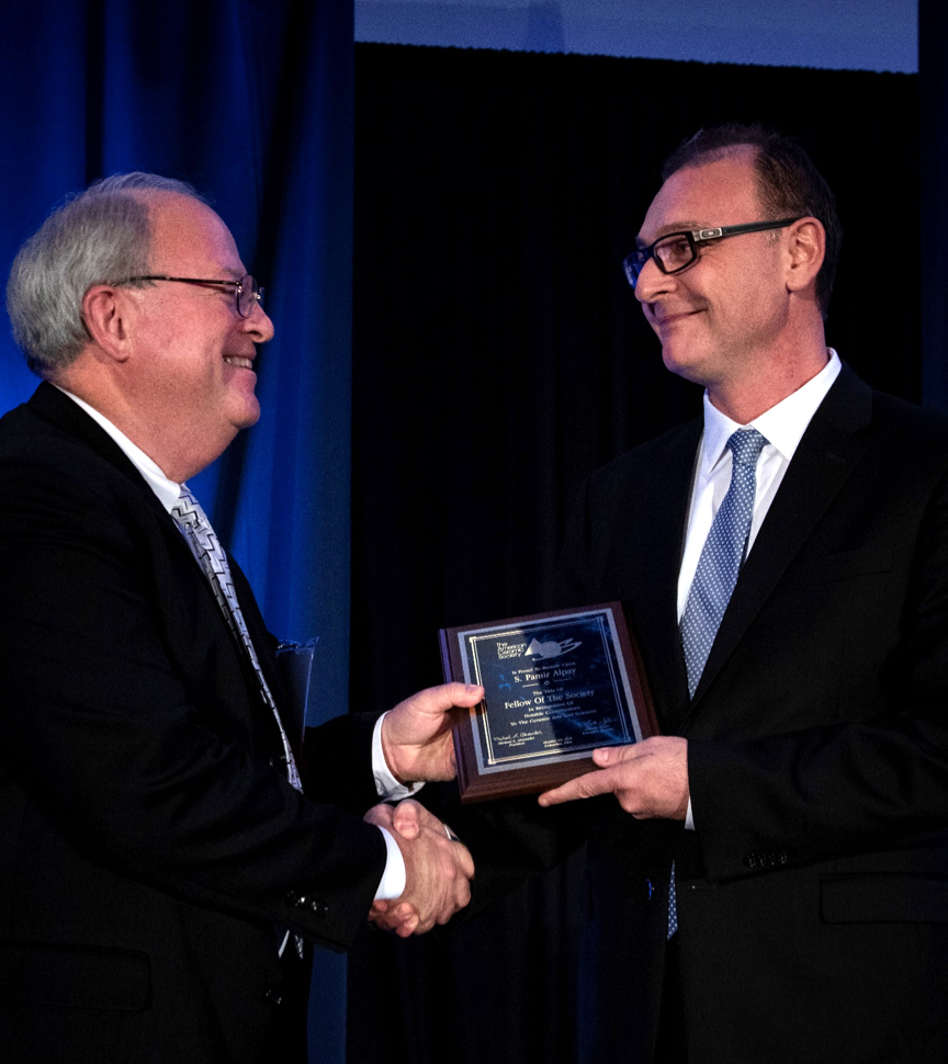 Dr. S. Pamir Alpay (right) accepts his Fellow of The Society award for the ACerS President Michael Alexander (left) at the Society’s annual banquet. 