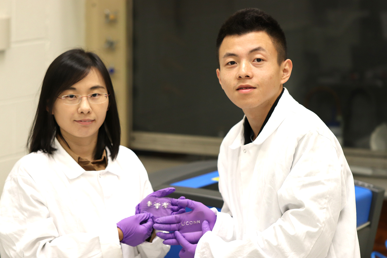 photo of Assistant Professor Wang and her Ph.D. students Yi Li holding morphable LCE structures and UCONN letters