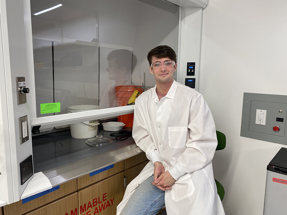 photo of Undergraduate student Jackson Kazsas sitting near a fume hood in an MSE Teaching Lab in Science 1.
