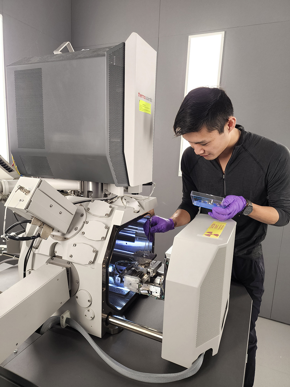 photo of Kyrus Tsai, MSE graduate student, loading a sample into the Teneo SEM at the Center for Advanced Microscopy and Materials Analysis (CAMMA) in the Innovation Partnership Building (IPB).